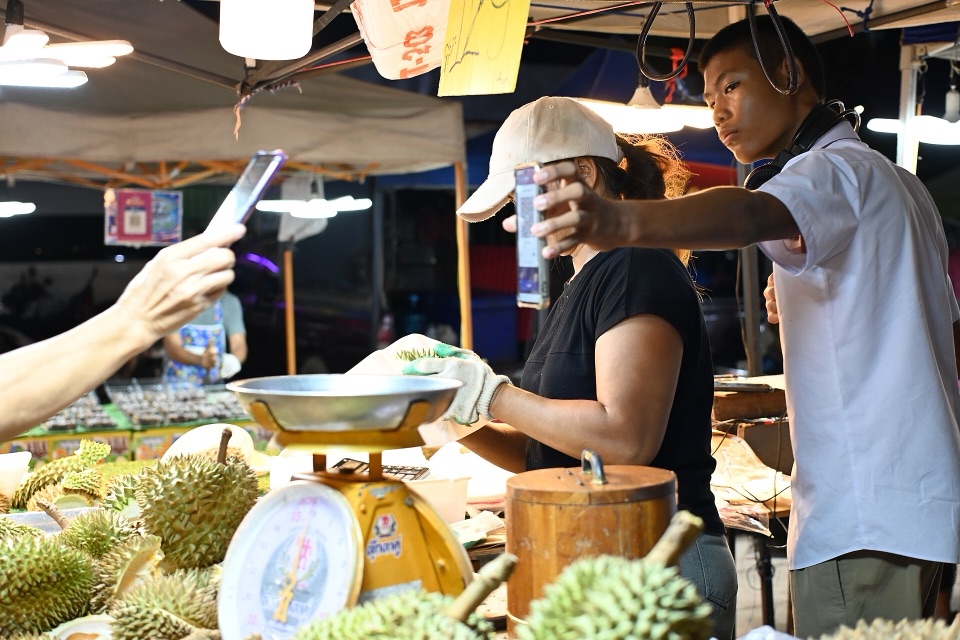 Pembeli memindai kode QR dengan ponsel di lapak pasar malam