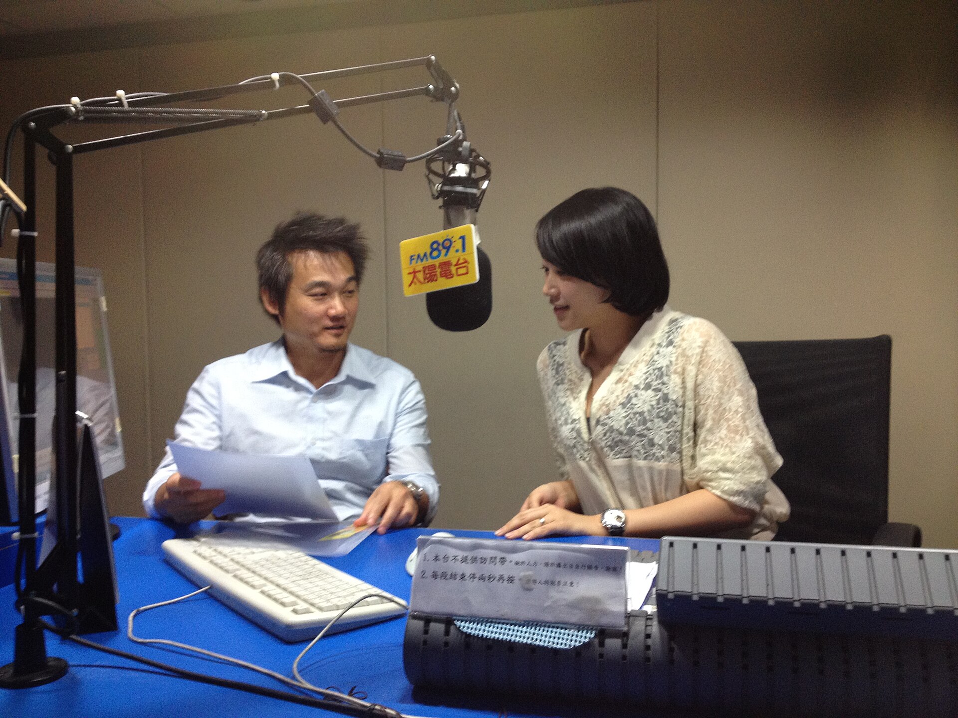 Dua orang merekam wawancara radio di studio dengan mikrofon